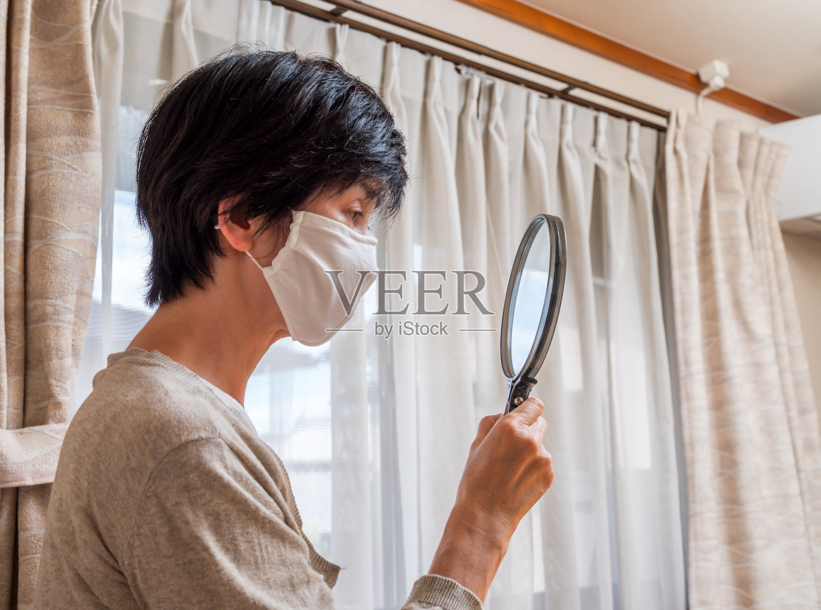 带着面具的中年妇女望着手里的镜子照片摄影图片