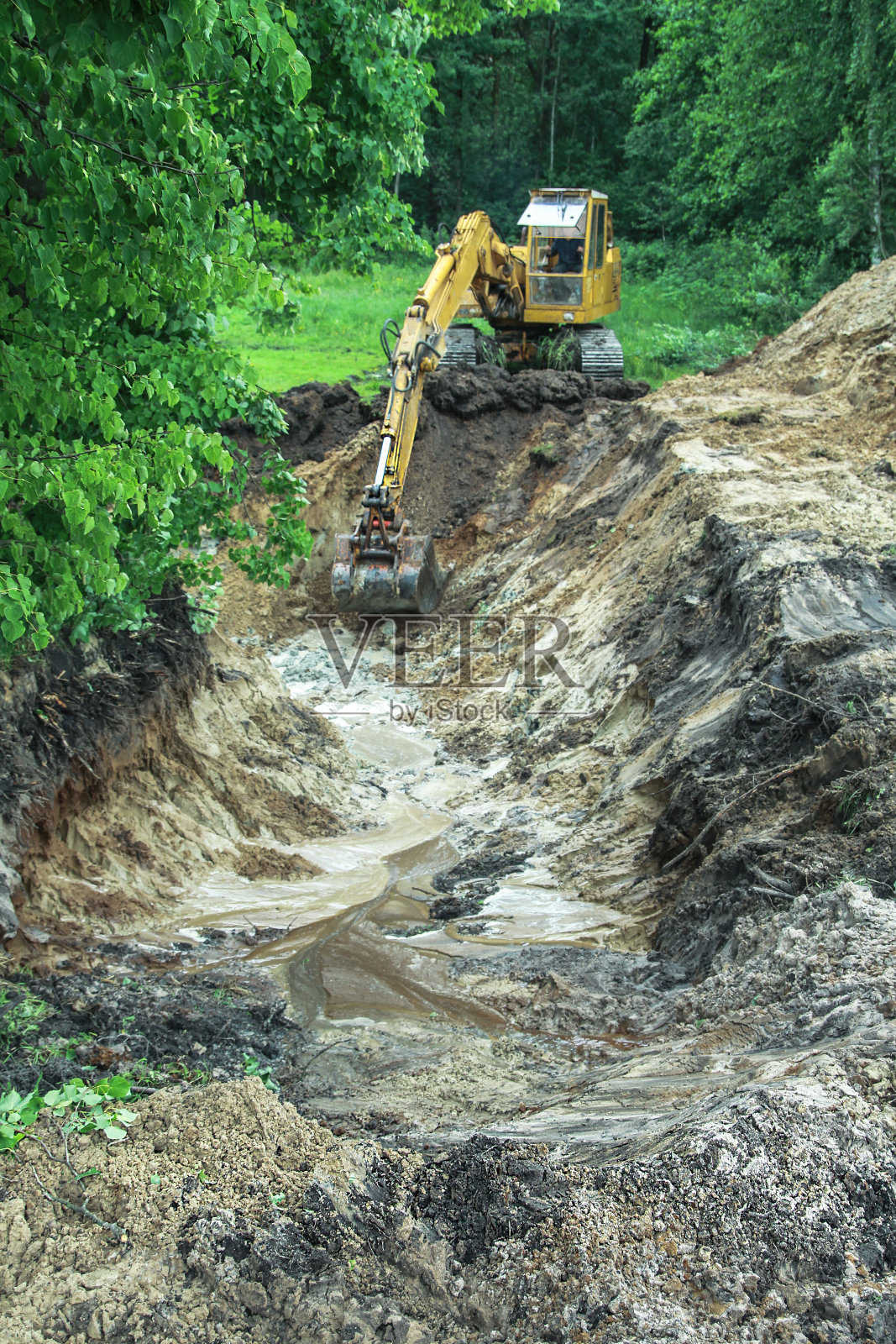 挖掘机为盖房子挖了一条大沟。一台拖拉机挖出一个已经蓄水池。设计库存背景照片摄影图片