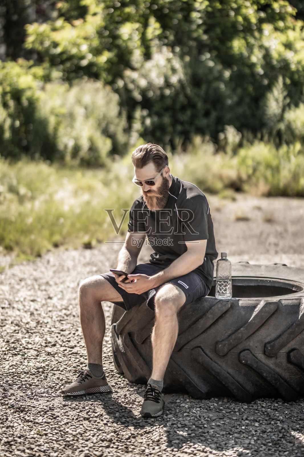 英俊的运动员与手机休息后交叉训练练习。健康的生活方式的概念。喝水照片摄影图片