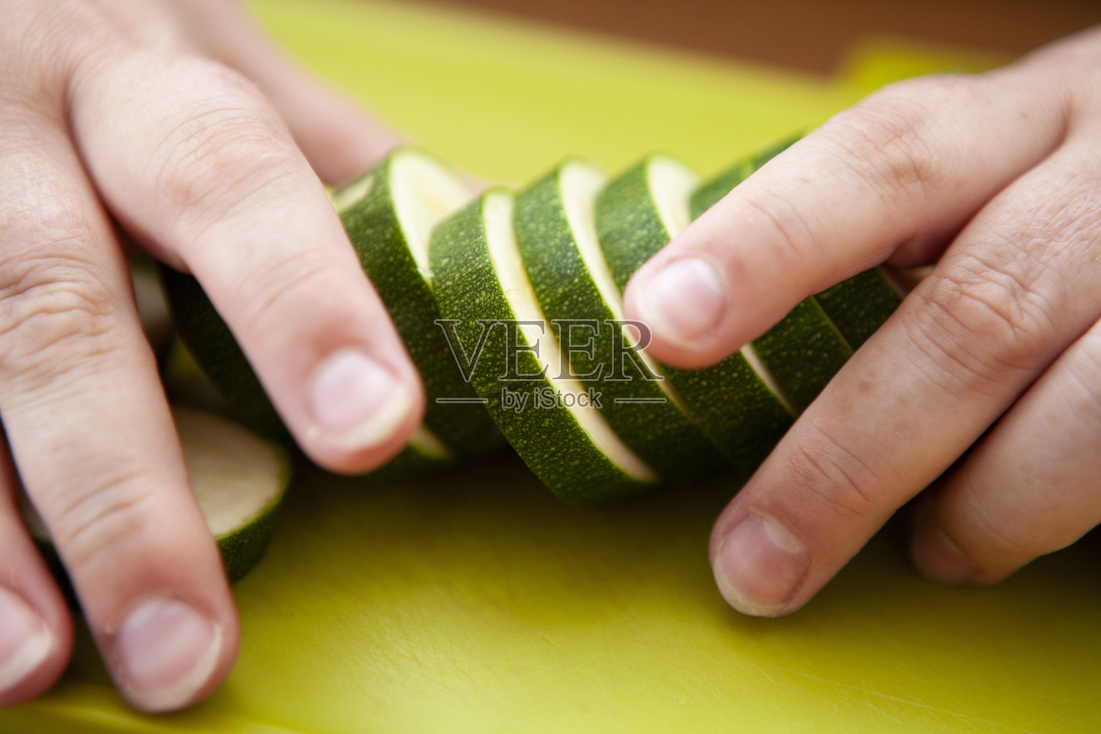 双手捧着绿菜板上的小胡瓜片照片摄影图片