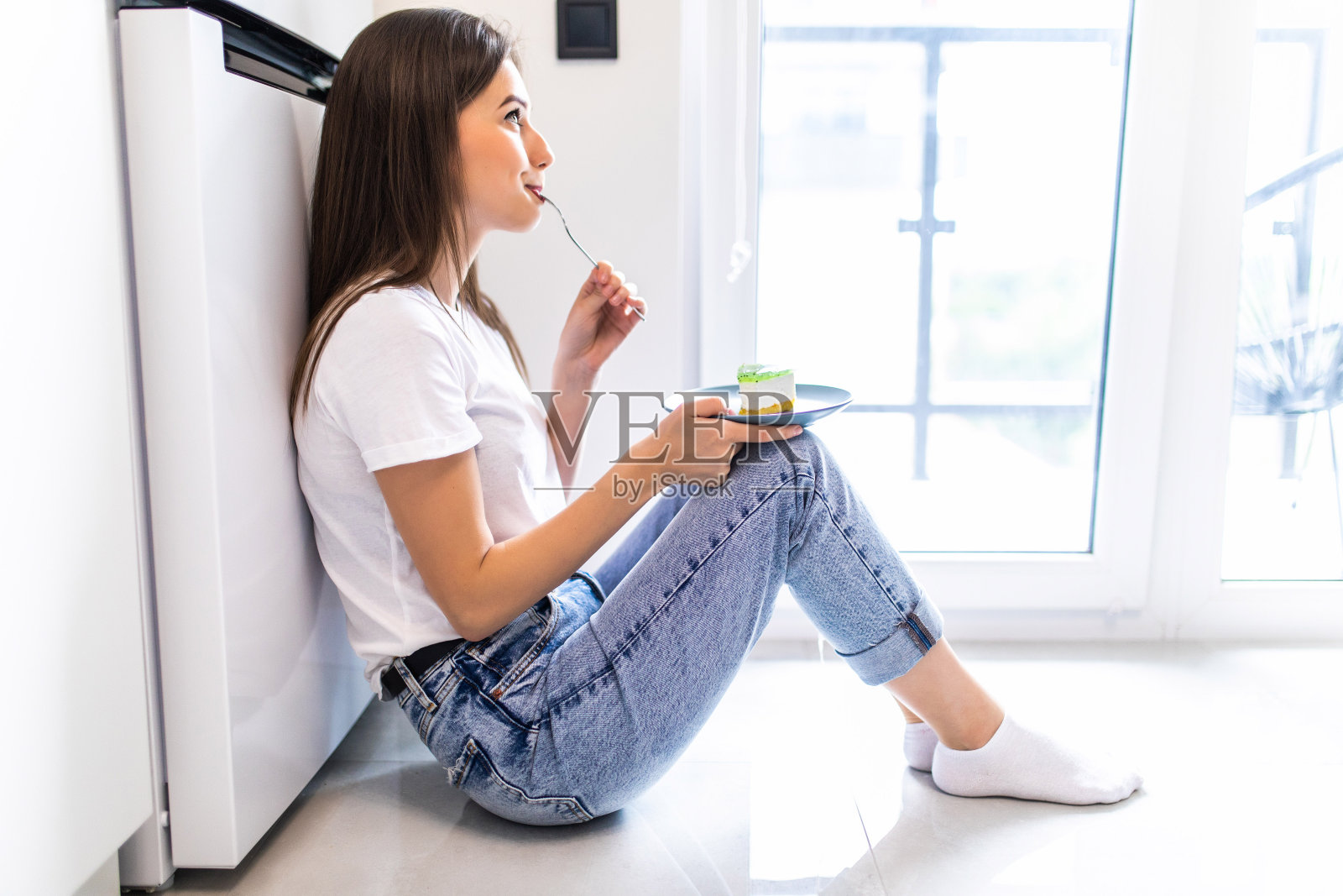 快乐的漂亮女人正坐在厨房里吃甜点。早上好概念照片摄影图片