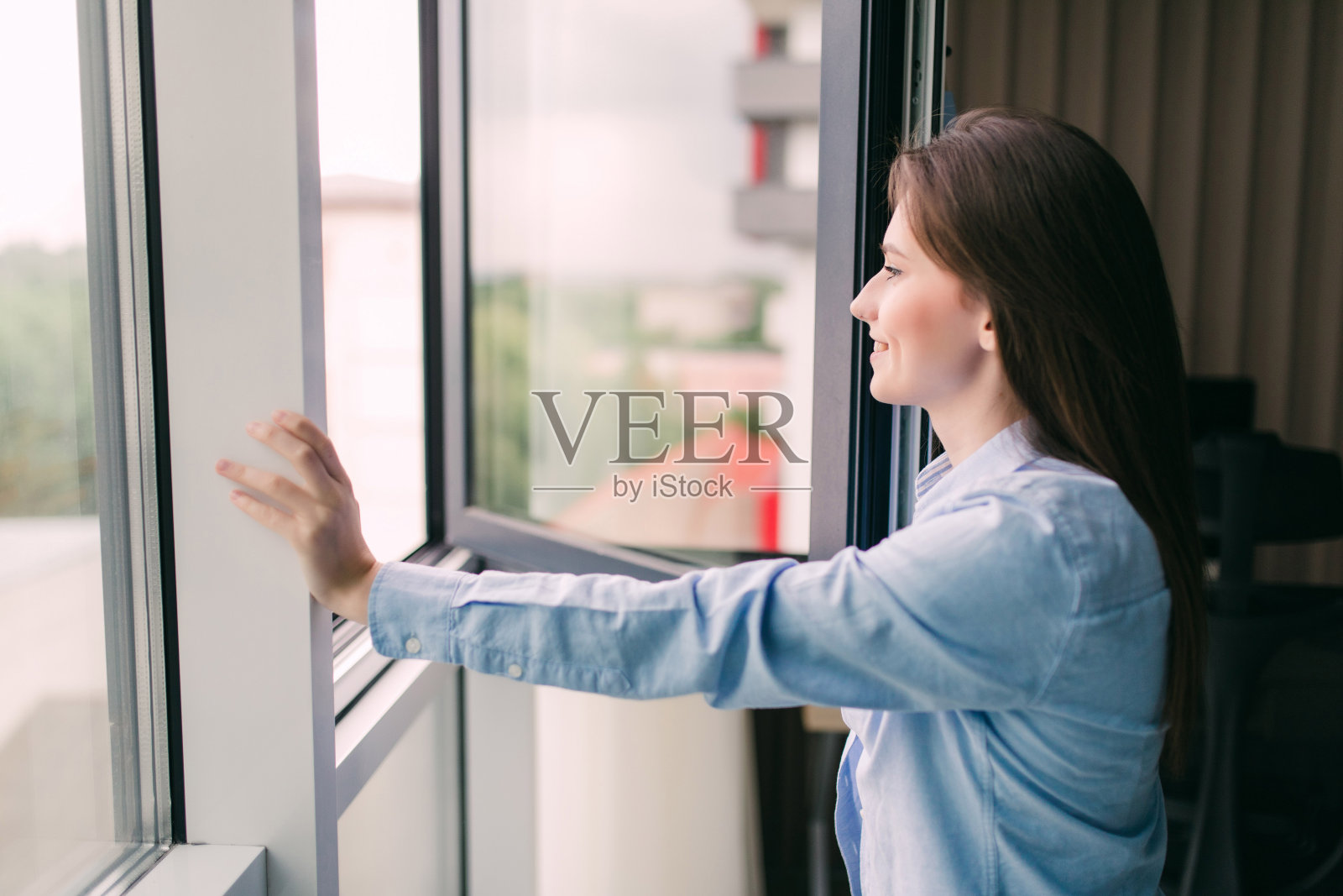 年轻女子早上在客厅打开窗户呼吸新鲜空气照片摄影图片