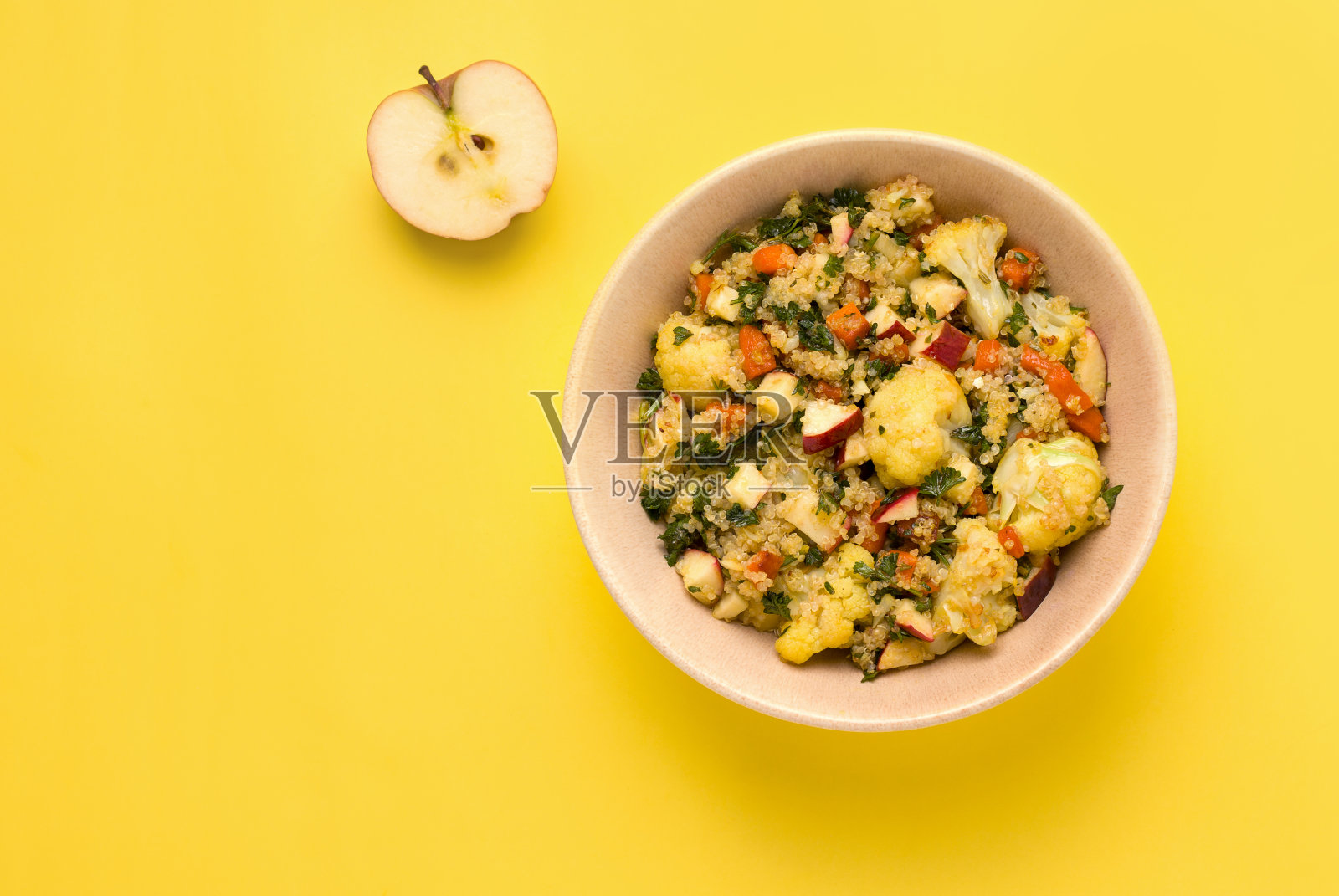 用花椰菜,藜麦,苹果和欧芹做的夏季沙拉,在黄色的背景上。本空间照片摄影图片