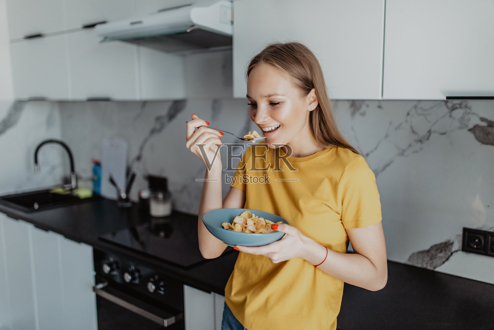 漂亮的年轻女子在厨房的玻璃碗里吃早餐照片摄影图片