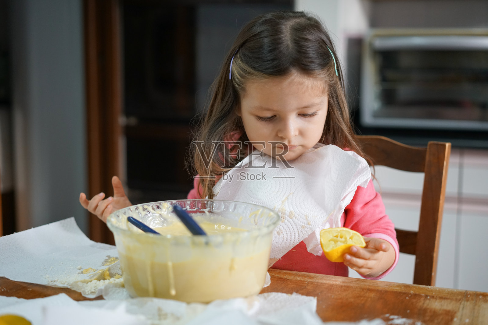 美丽的小女孩在隔离期间烹饪时使用柠檬。照片摄影图片