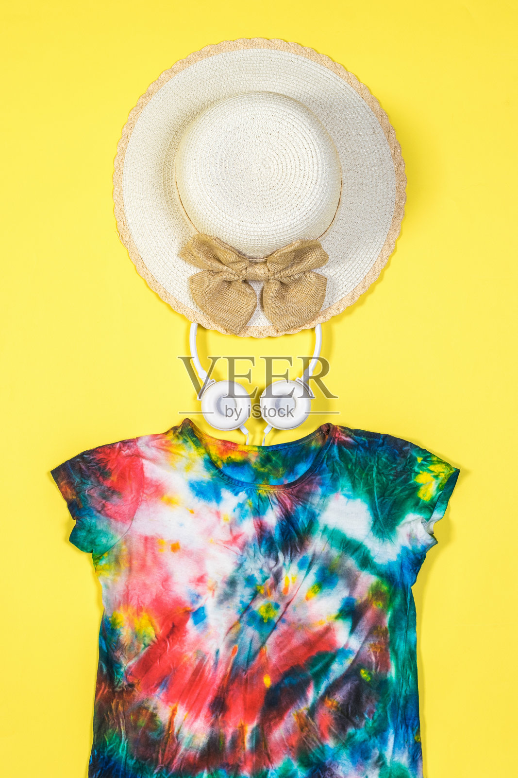 帽子,耳机和黄色背景的扎染t恤。平的。照片摄影图片