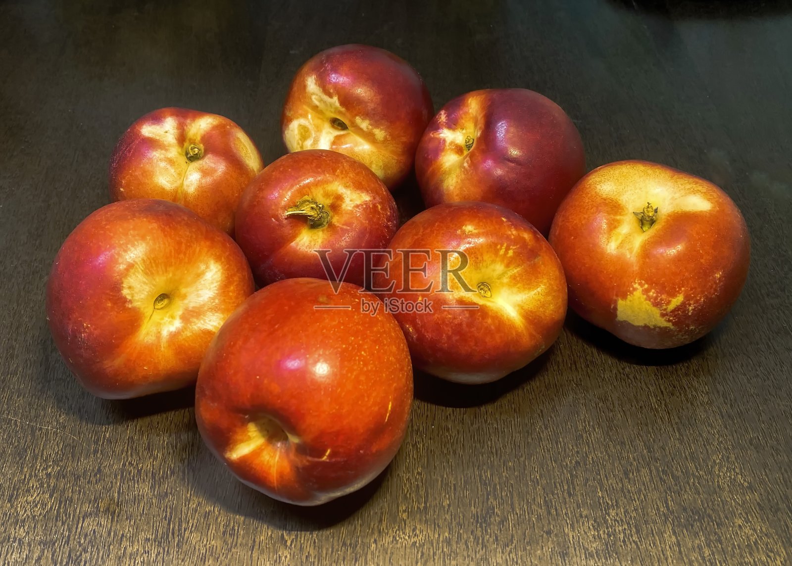 油桃,一种果皮光滑、颜色鲜艳、果肉结实的桃子,在深棕色木桌上照片摄影图片