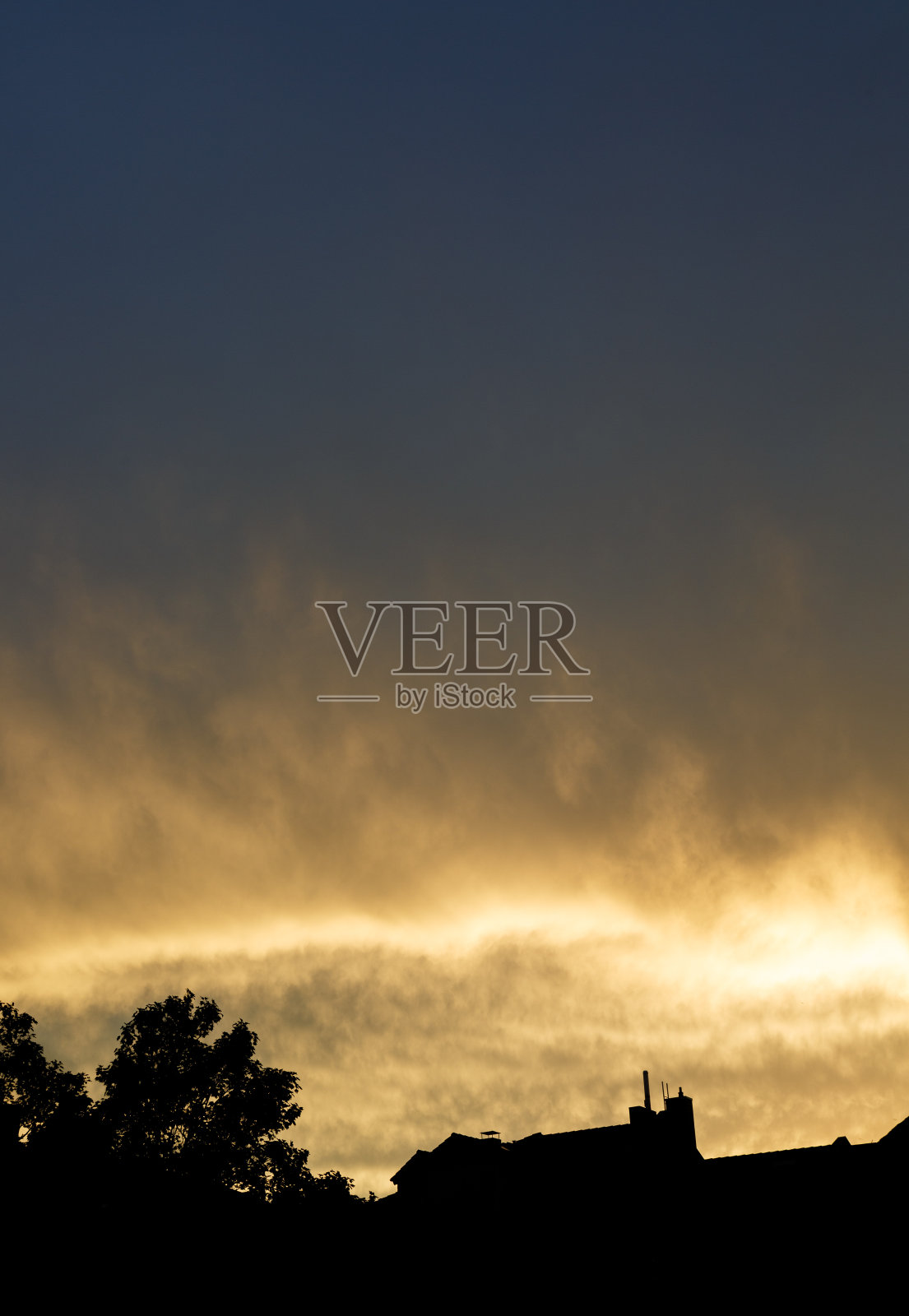 日落与戏剧性的天空和云彩在屋顶上照片摄影图片