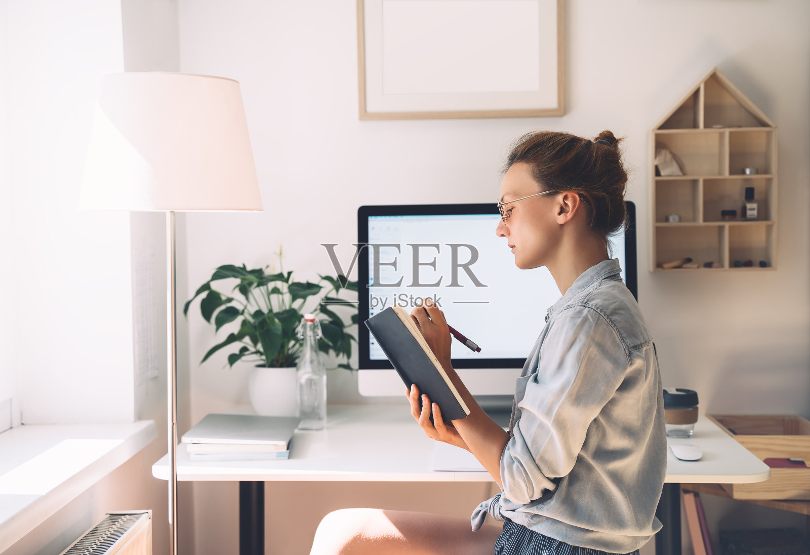 女性自由职业者室内家庭办公室的概念。戴眼镜的女孩与新的创业项目合作。照片摄影图片