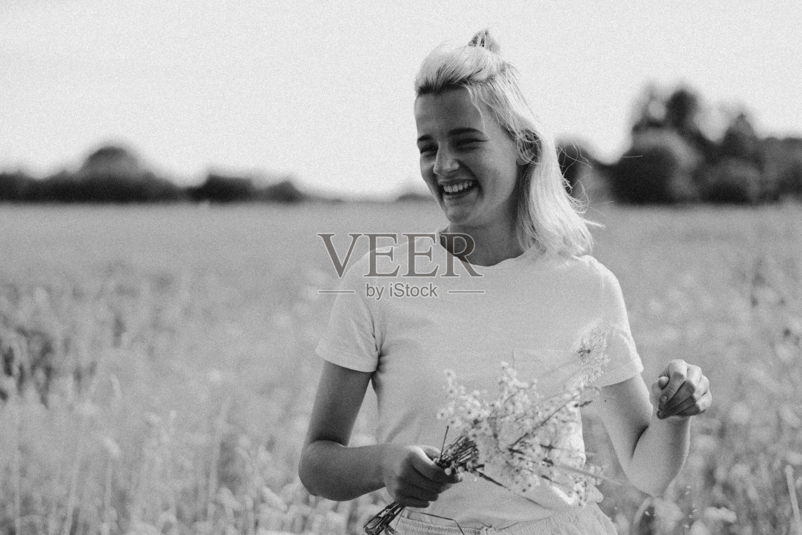 黑白照片美丽的年轻女孩在草地上和鲜花。的生活方式。享受大自然和夏天。照片摄影图片