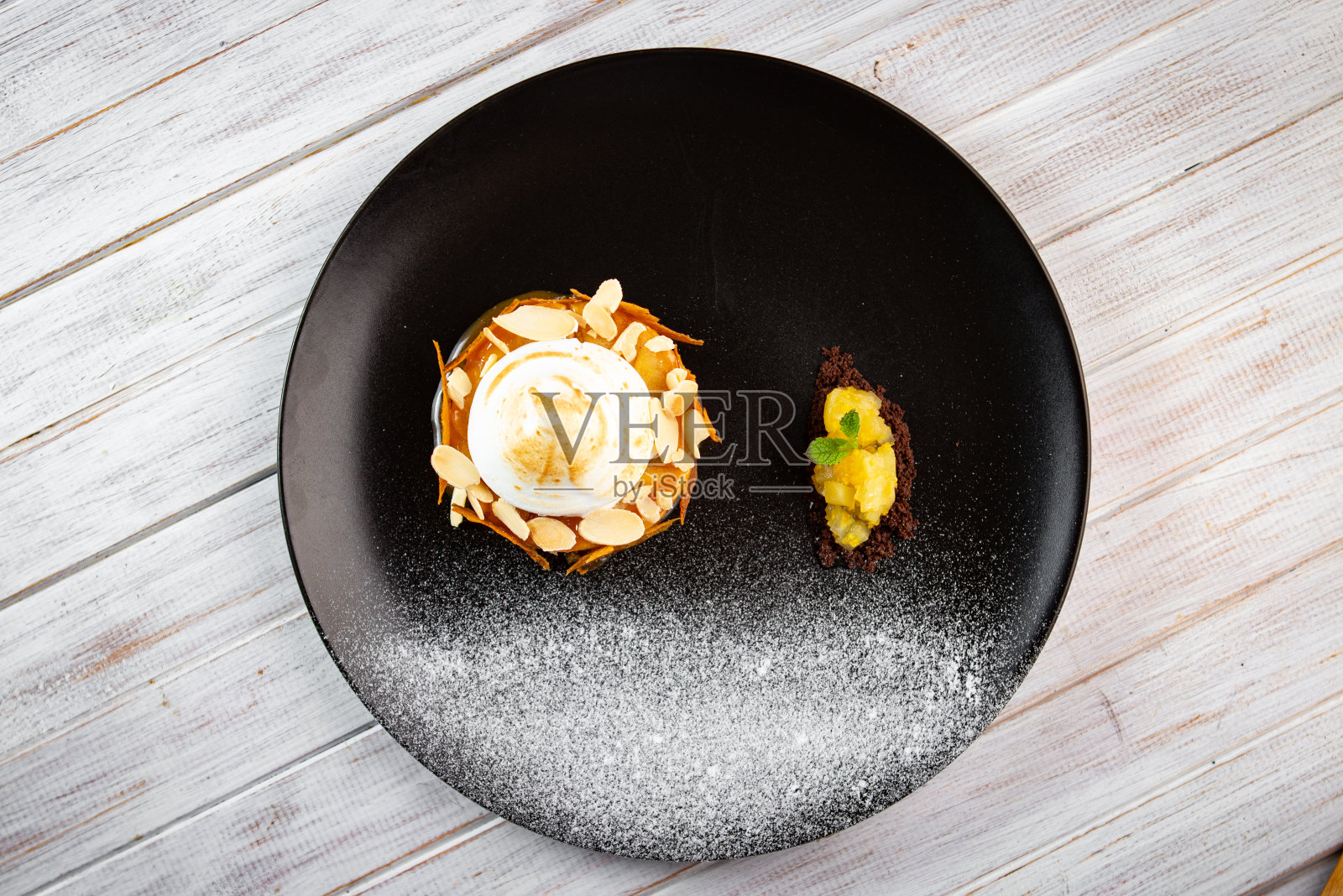 白色背景的黑色盘子上放着一份涂着奶油的苹果派。夏洛特坚果烘焙甜点,俯视图照片摄影图片