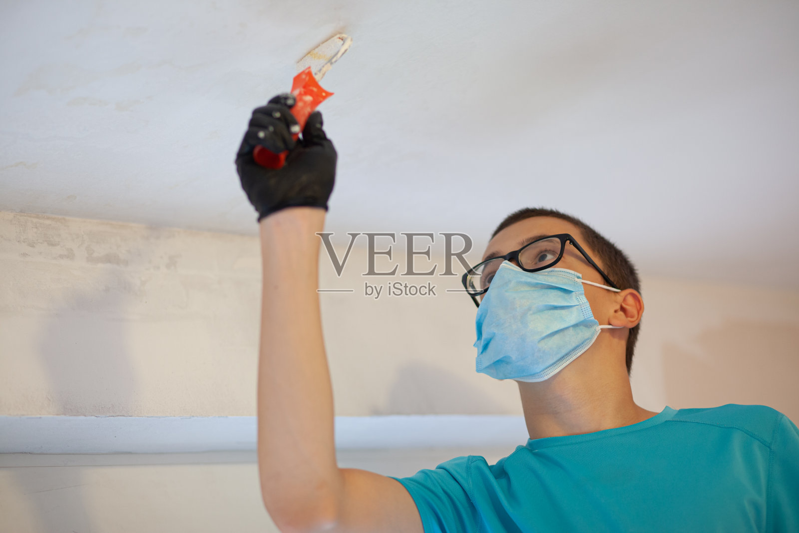 少年用油漆滚筒刷他的房间照片摄影图片