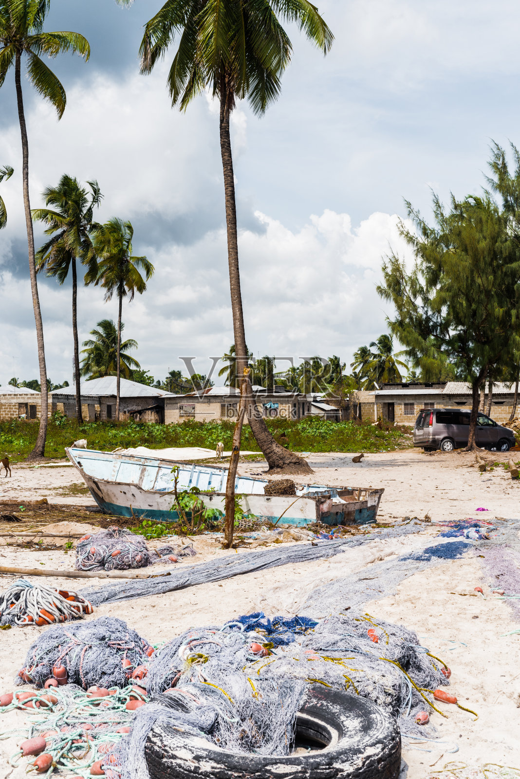 海滩上的渔网和船,背景是房子照片摄影图片