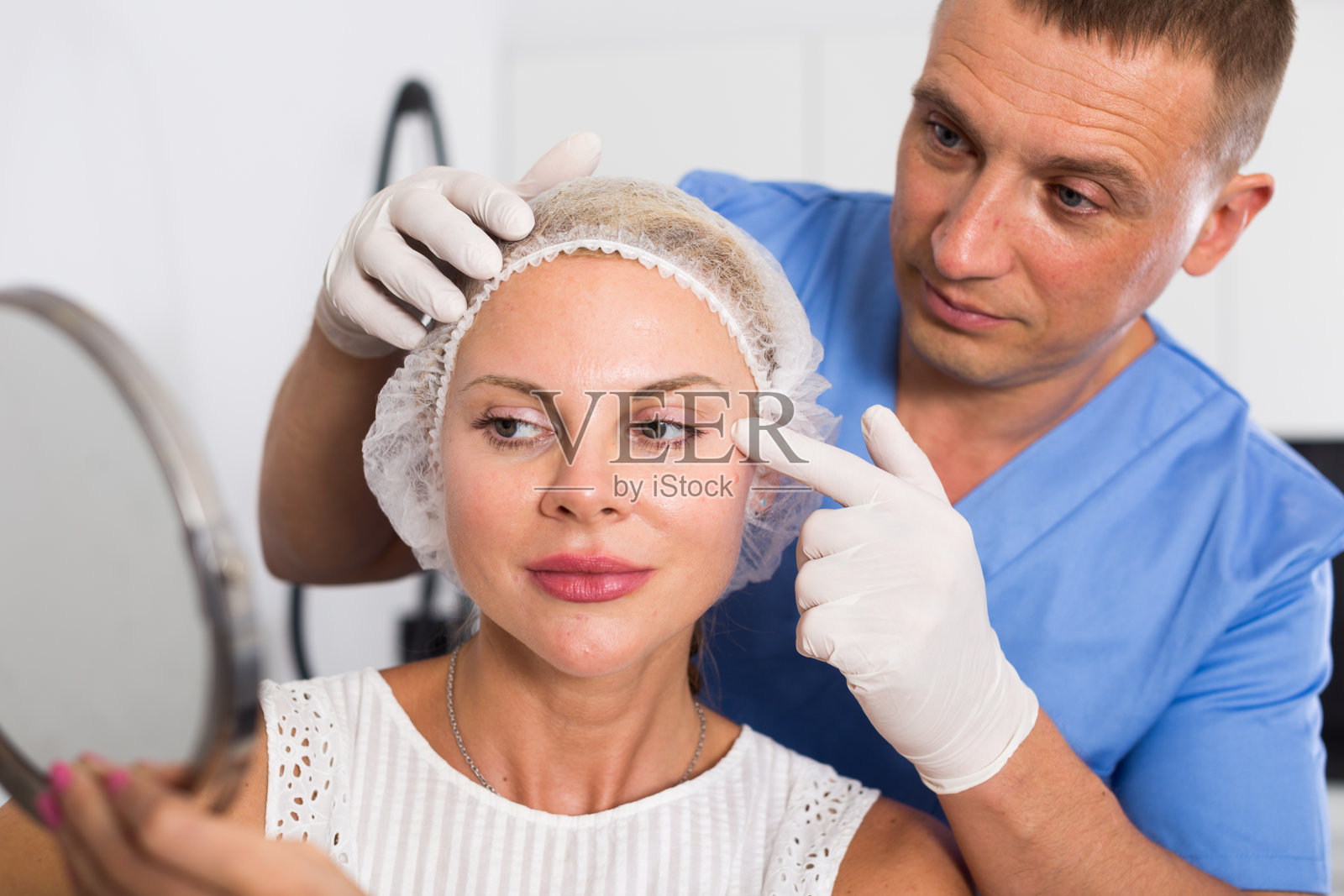 手术前,医生正在镜子后面为女病人做检查照片摄影图片