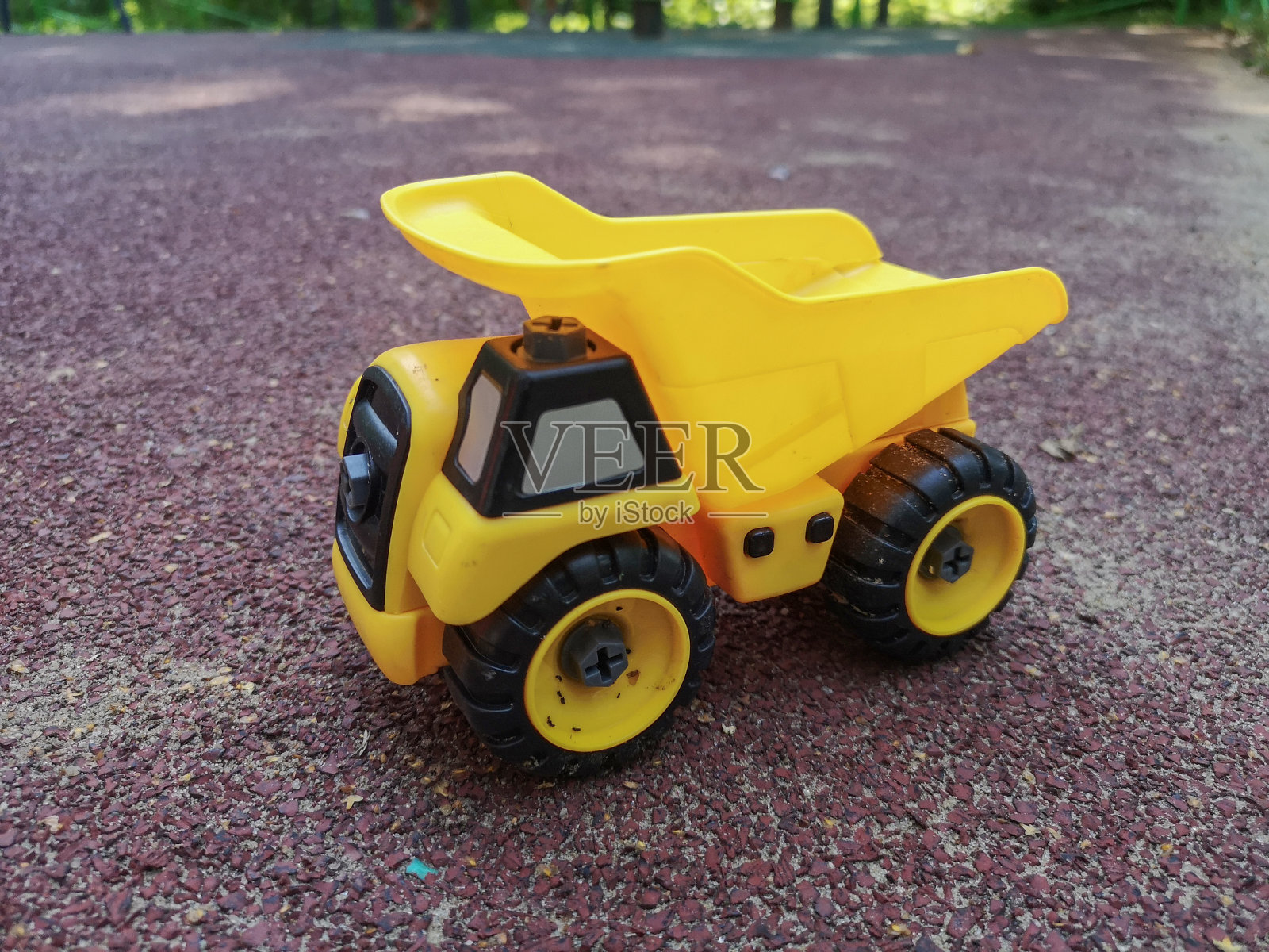 黄色的小玩具卡车在操场的橡胶套上照片摄影图片
