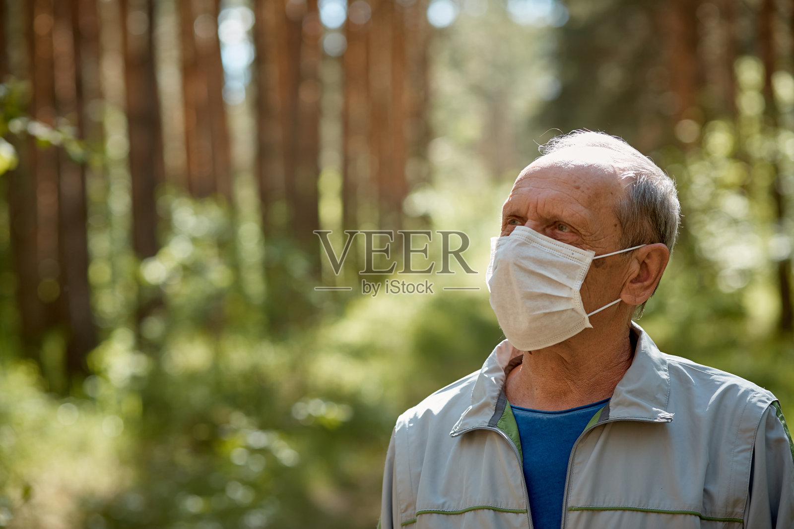 一位戴着防护面具的老人在公园散步,在隔离后的新鲜空气中散步,这是针对病毒的预防措施照片摄影图片