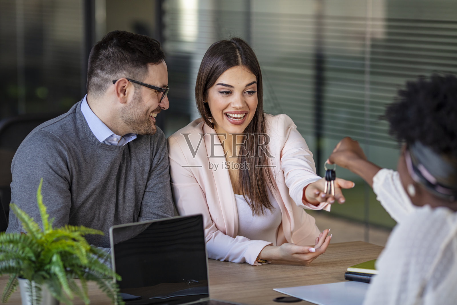 幸福的夫妇买了他们的新家,并从房地产经纪人那里得到钥匙。照片摄影图片