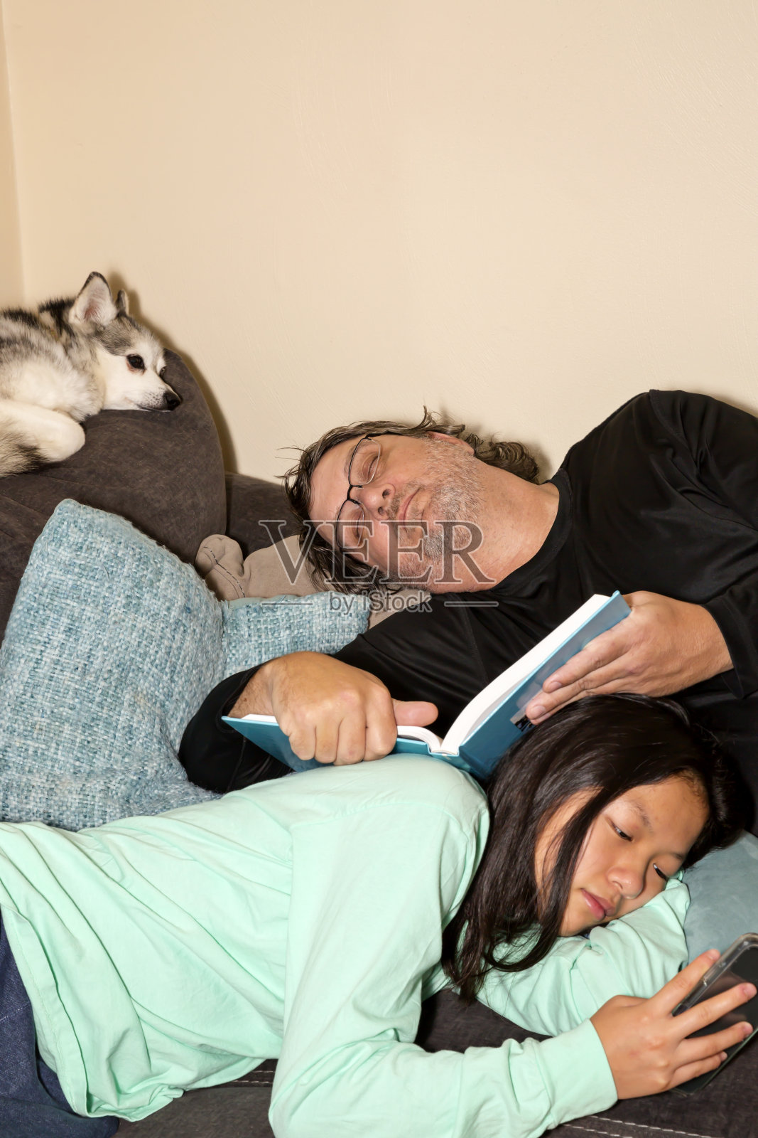 当爸爸睡在她身后时,小女孩在她的手机上享受社交媒体照片摄影图片