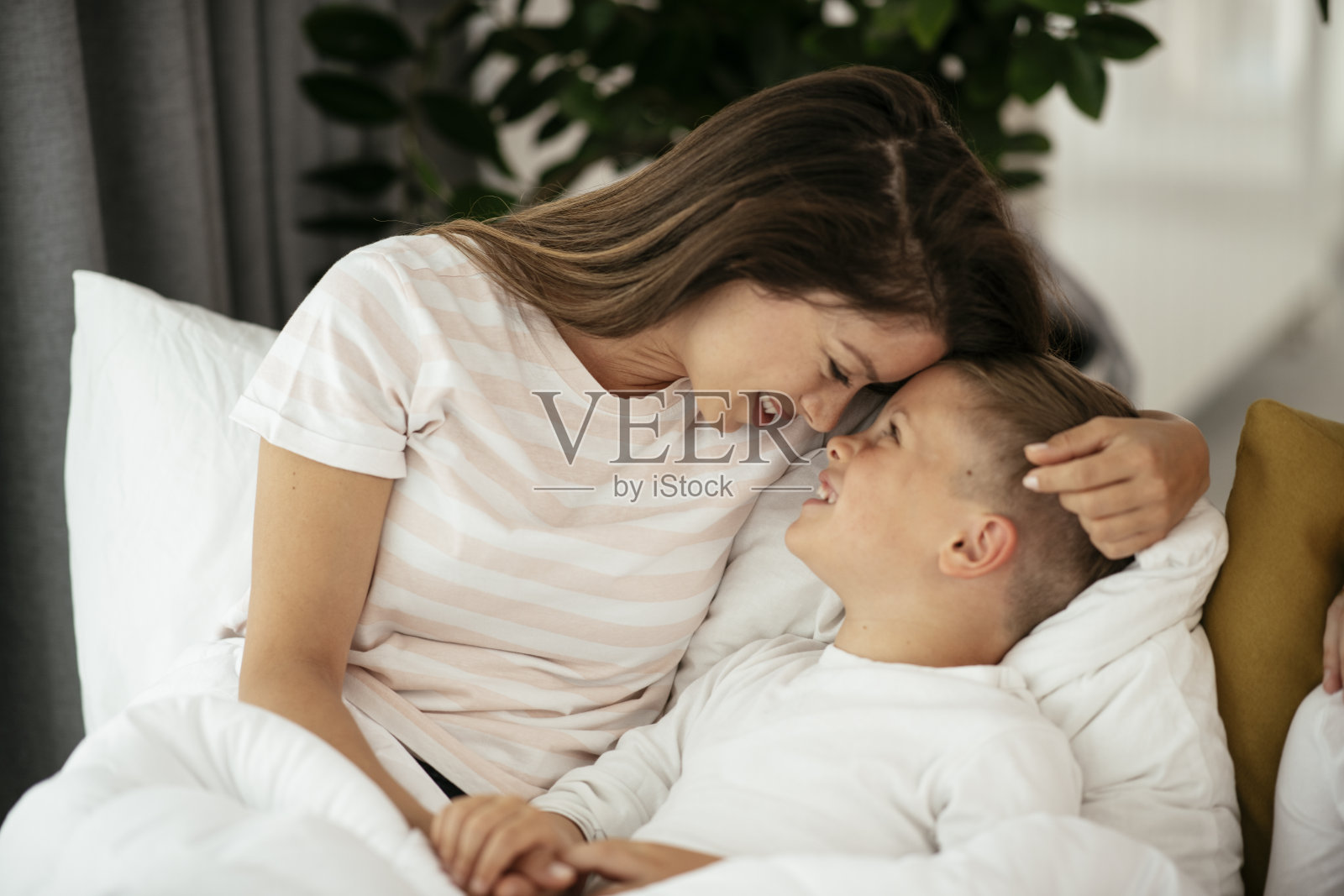 快乐的母亲和儿子在沙发上休息。照片摄影图片