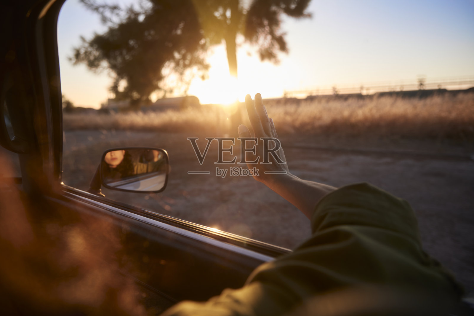 年轻女子在公路上与手臂在日落窗外照片摄影图片