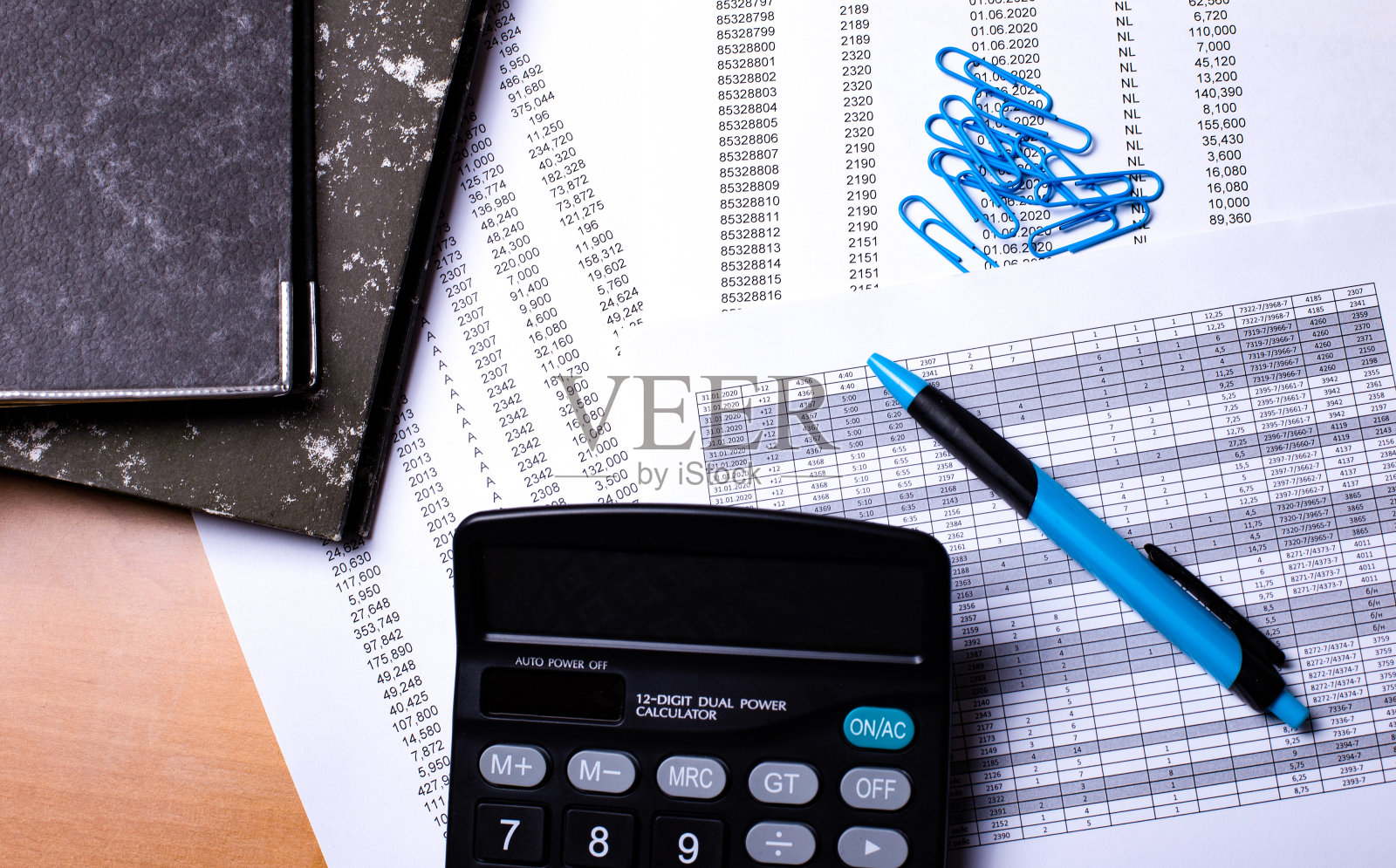 木桌上放着报告、计算器、蓝色回形针和一支笔。经营理念接近照片摄影图片
