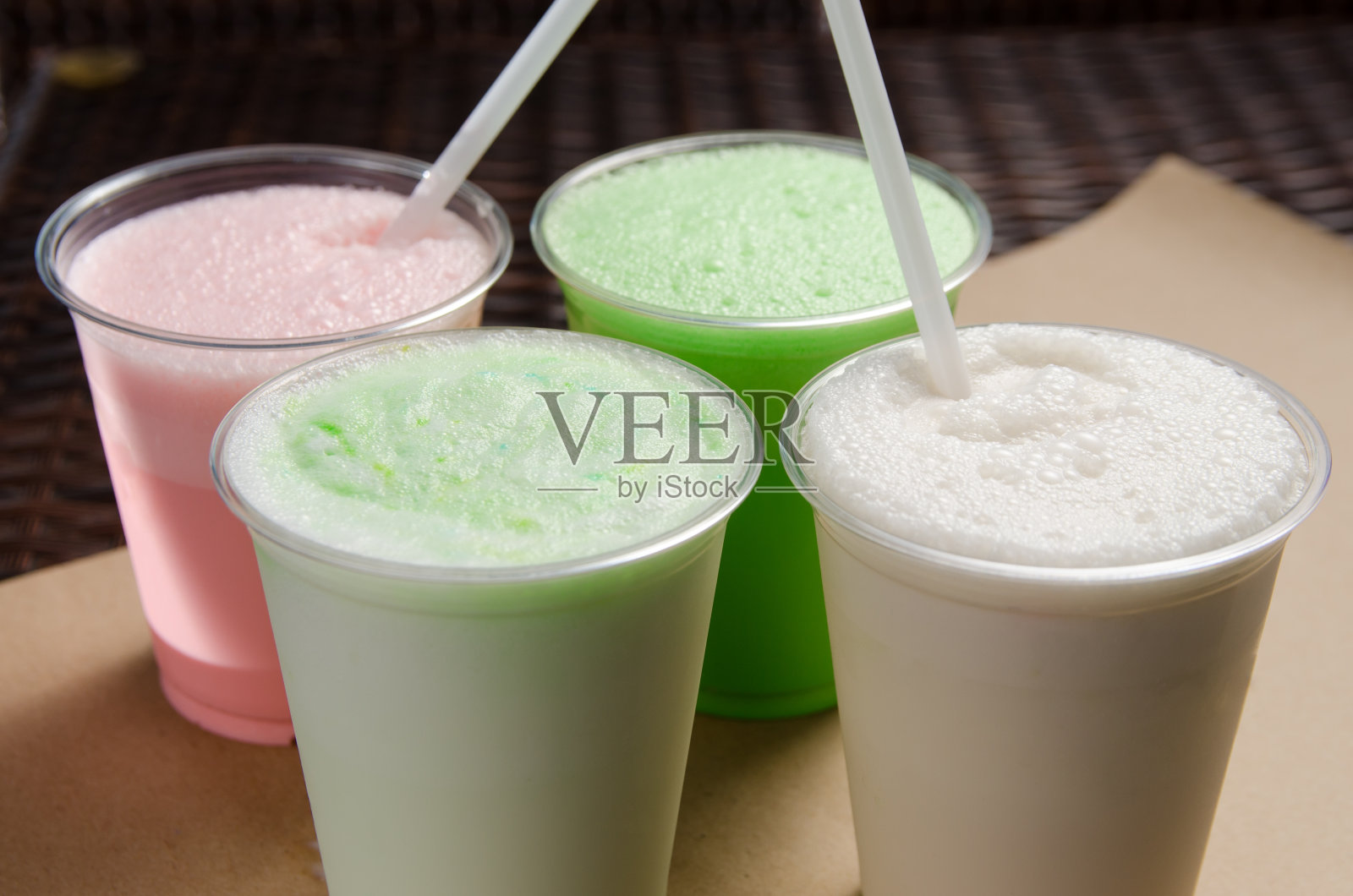 白色、粉色和绿色奶昔装在带有吸管的透明杯子里照片摄影图片