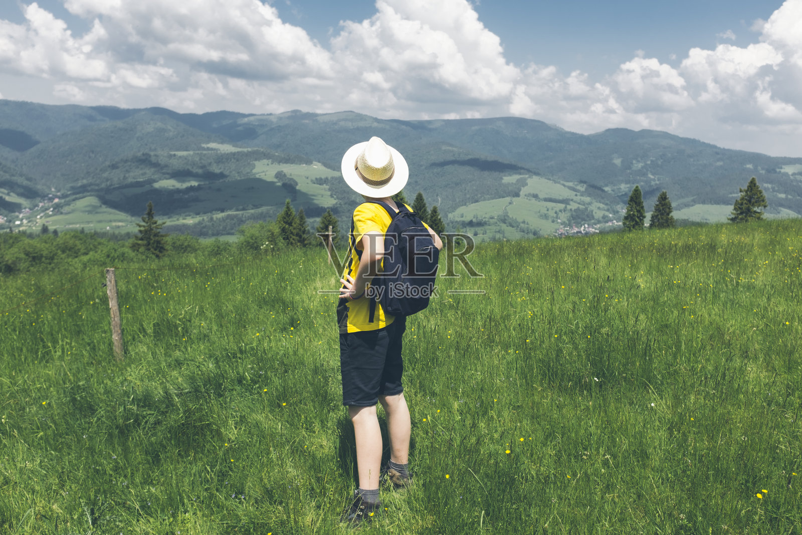 十几岁的男孩站在山上看风景,爬上山后休息——风景全景,积极的生活方式。照片摄影图片