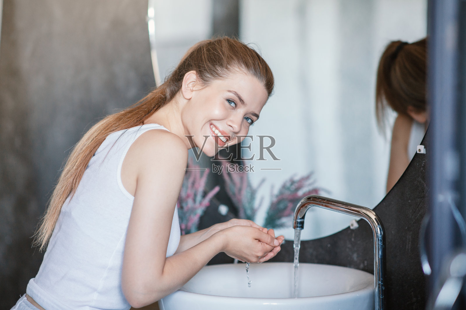日常生活的方式。微笑的小女孩在浴室的水槽洗手照片摄影图片