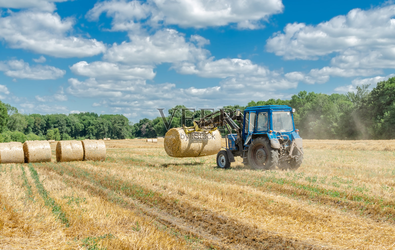 圆捆的稻草和田里的拖拉机照片摄影图片