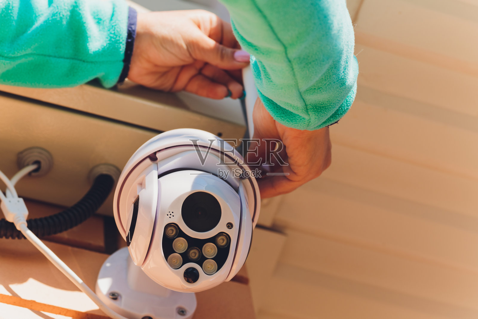 女技术员在墙上安装闭路电视摄像头。照片摄影图片