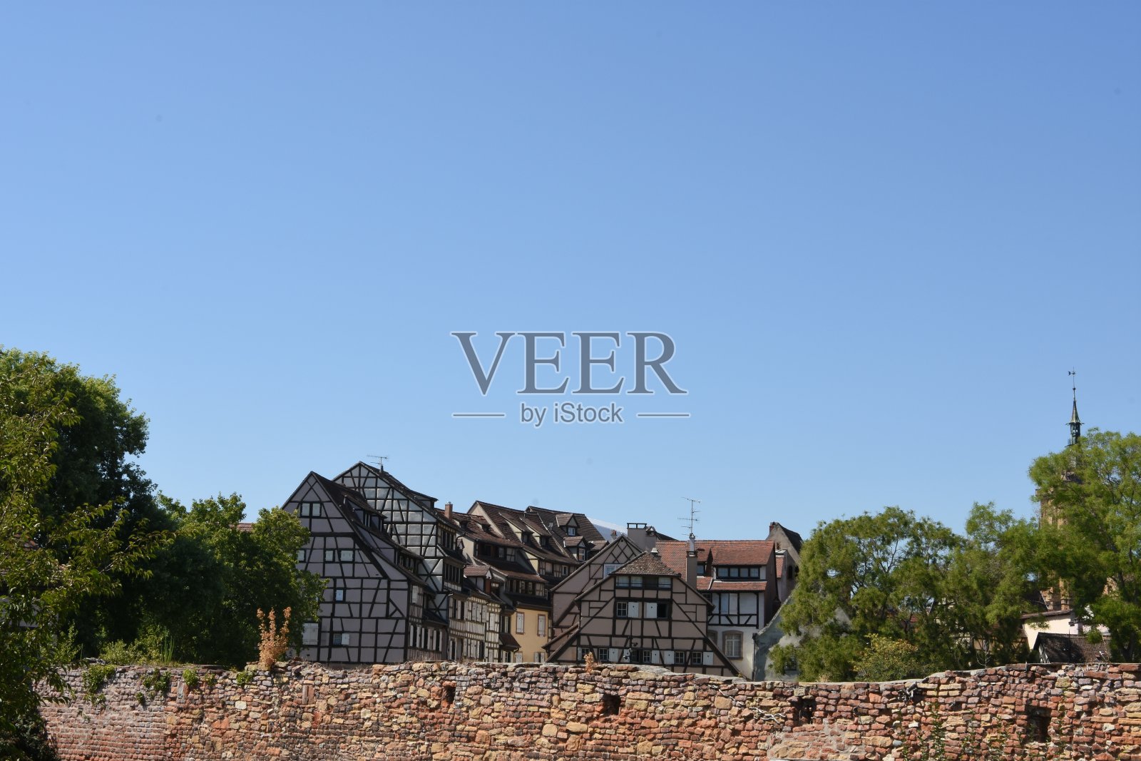 科尔马,法国东北部Grand Est地区的一个小镇,蓝色的天空下,红砖墙后面的中世纪和文艺复兴早期的半木质建筑。照片摄影图片