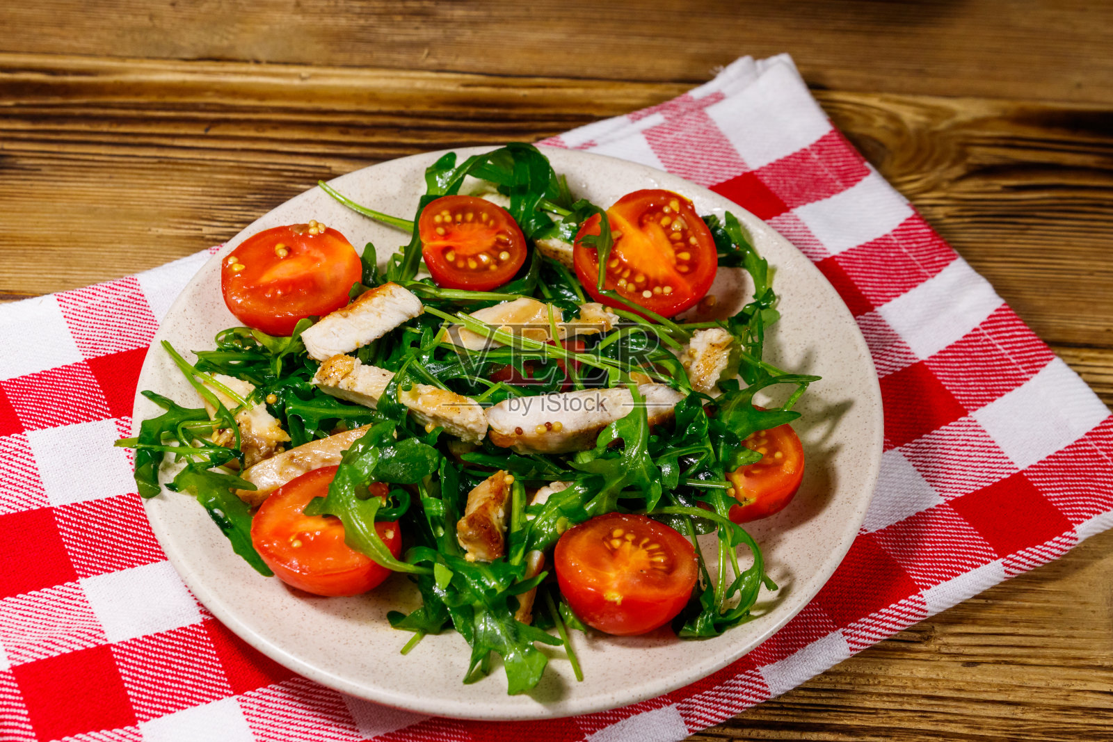 美味的炸鸡胸肉沙拉,新鲜芝麻菜和樱桃番茄放在木桌上照片摄影图片