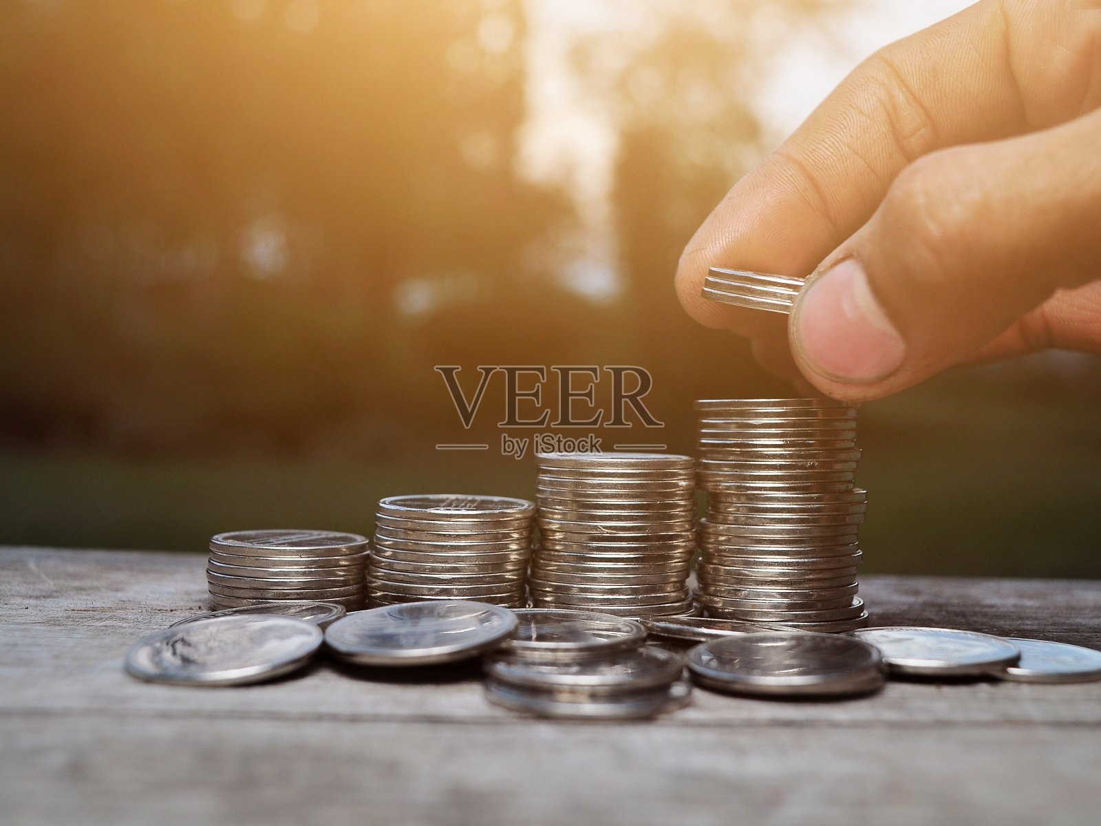 手把硬币放在硬币堆里。硬币的楼梯照片摄影图片