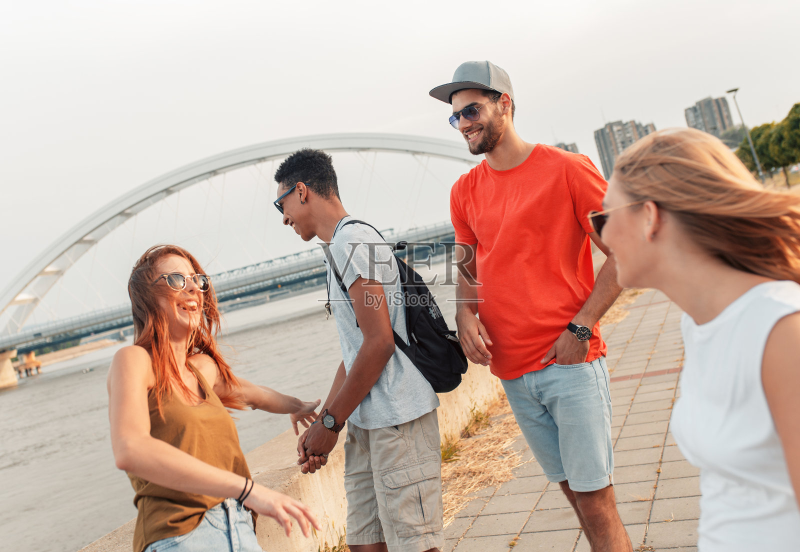 一群兴高采烈的朋友在河边散步。照片摄影图片