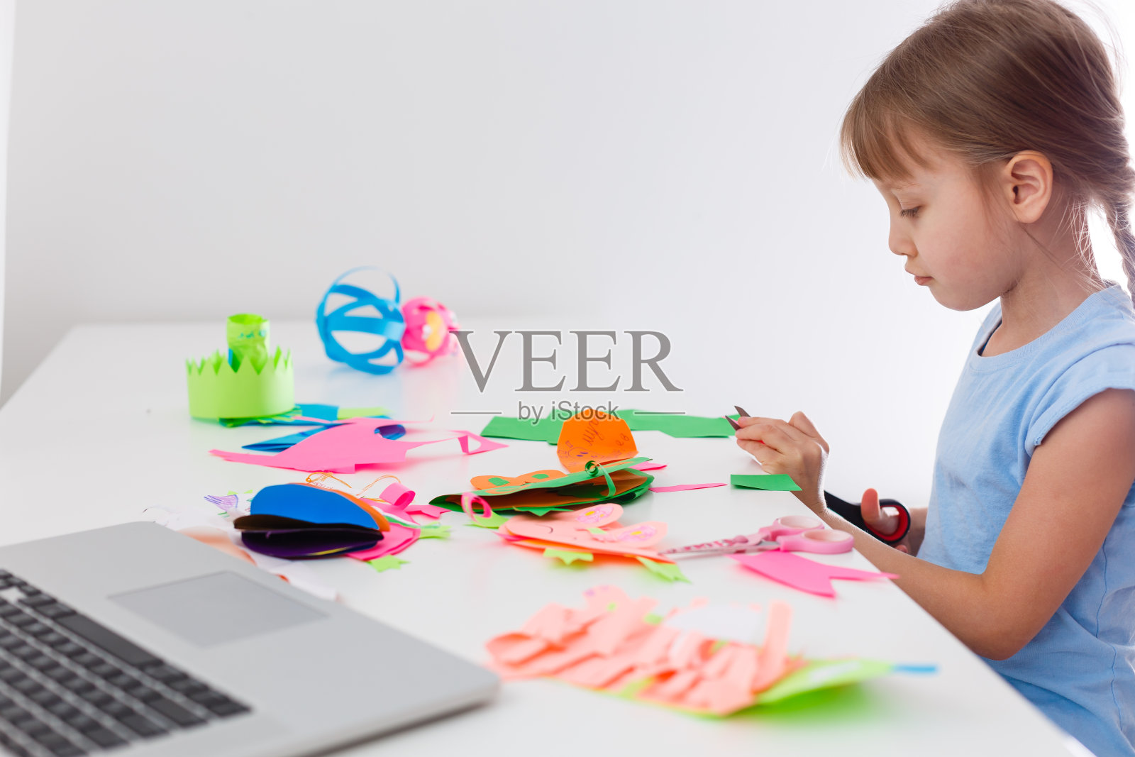 小女孩剪纸写真工艺品活动呆在家里远离新冠疫情危机。儿童用剪刀剪纸在线学习。在家教育孩子。照片摄影图片