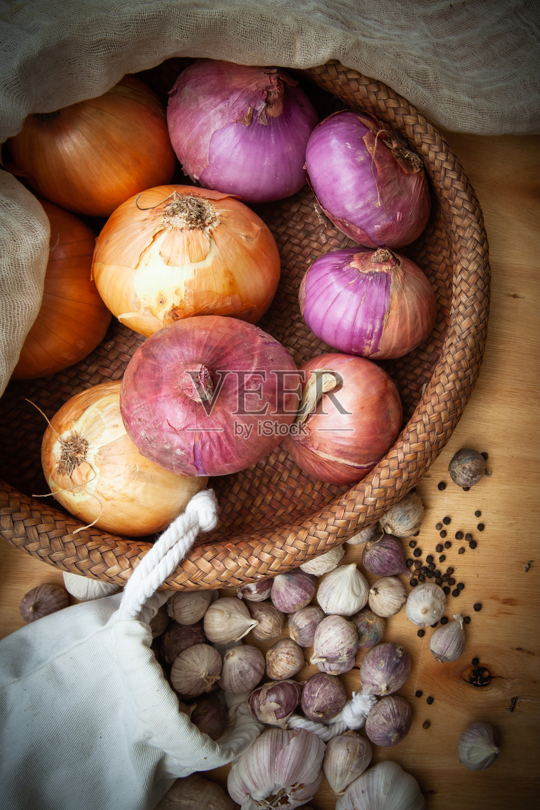 大蒜,黑胡椒和洋葱放在一个篮子里放在木地板上,背景照片摄影图片