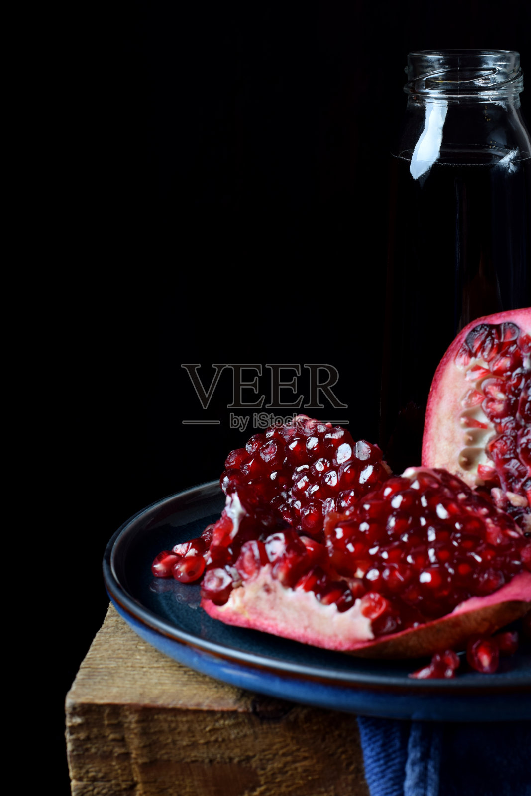 蓝色的盘子里放着成熟的石榴和一瓶鲜榨的果汁照片摄影图片