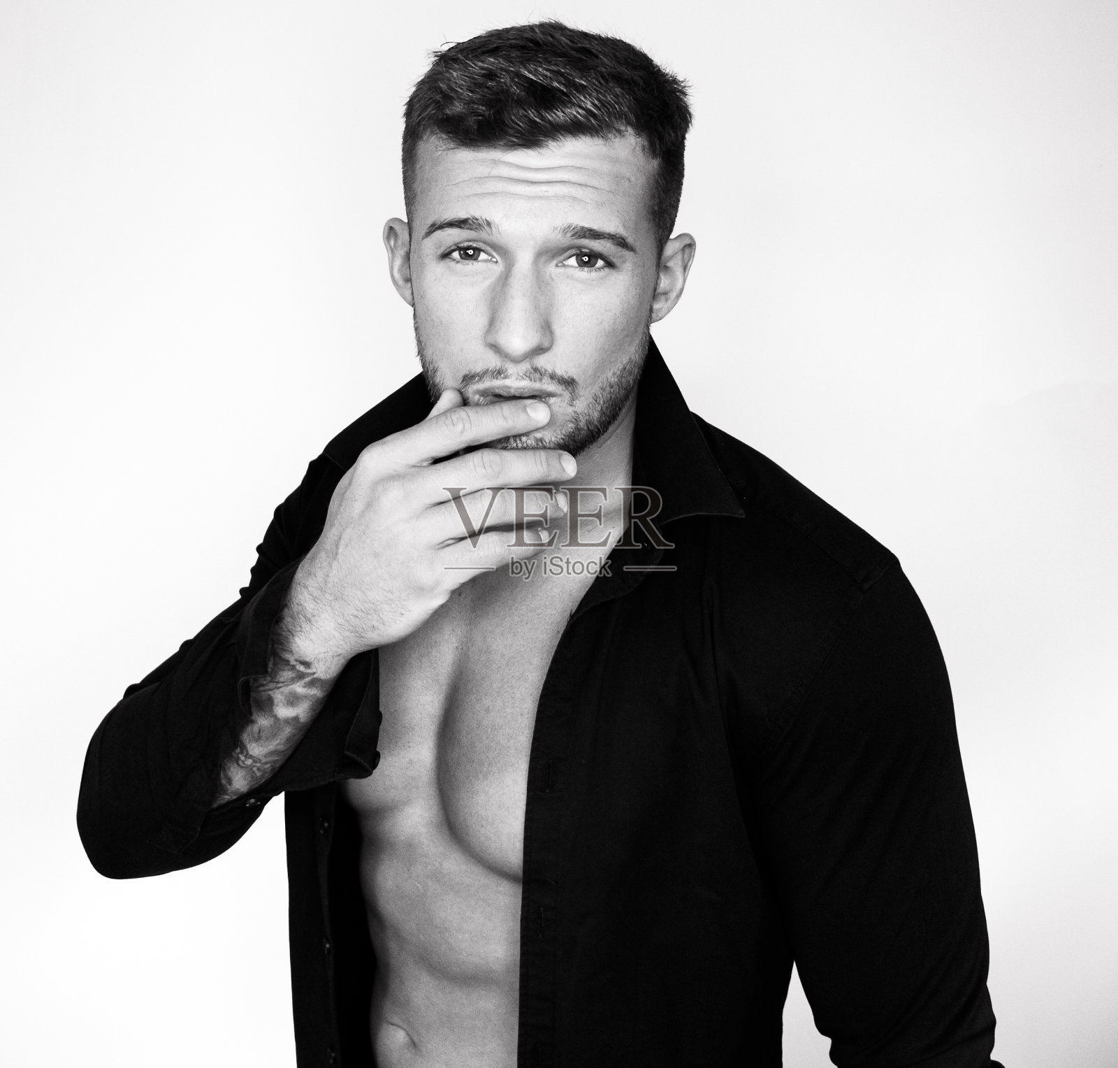 有魅力的男人穿着白衬衫,孤立地靠墙坐着照片摄影图片