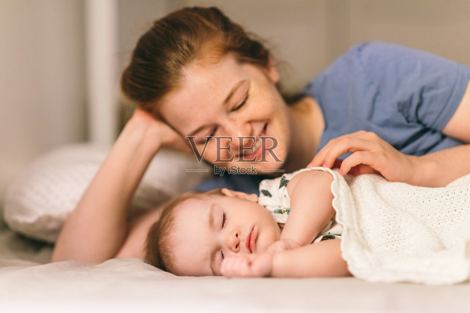 一个九个月大的婴儿和他的妈妈睡在床上。与父母同寝对家庭的好处照片摄影图片