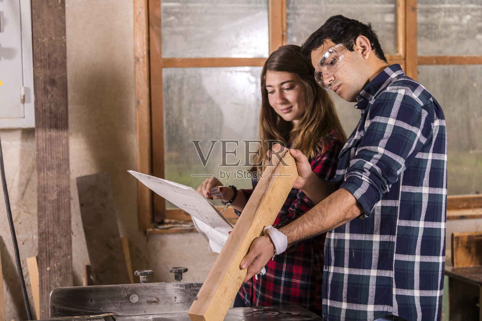一对年轻夫妇在木工作坊里。照片摄影图片