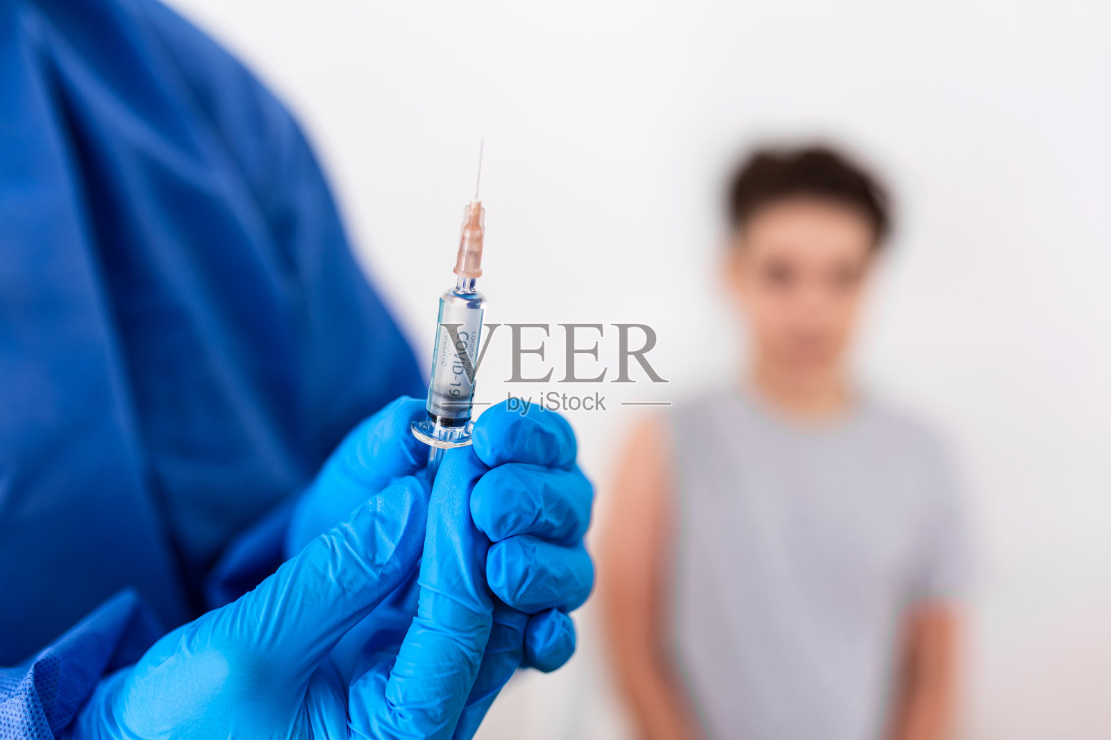 接种疫苗。专业医生戴着蓝色无菌手套拿着注射器给戴着医用口罩的小男孩进行注射。免疫、医药和保健。Covid19,冠状病毒疫苗照片摄影图片