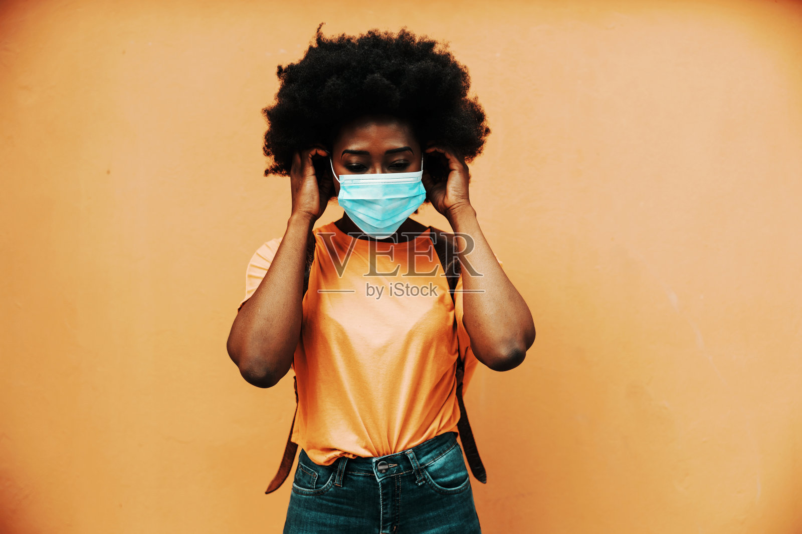 年轻迷人的卷发非洲妇女戴着口罩,以防止冠状病毒/冠状病毒19的传播。照片摄影图片