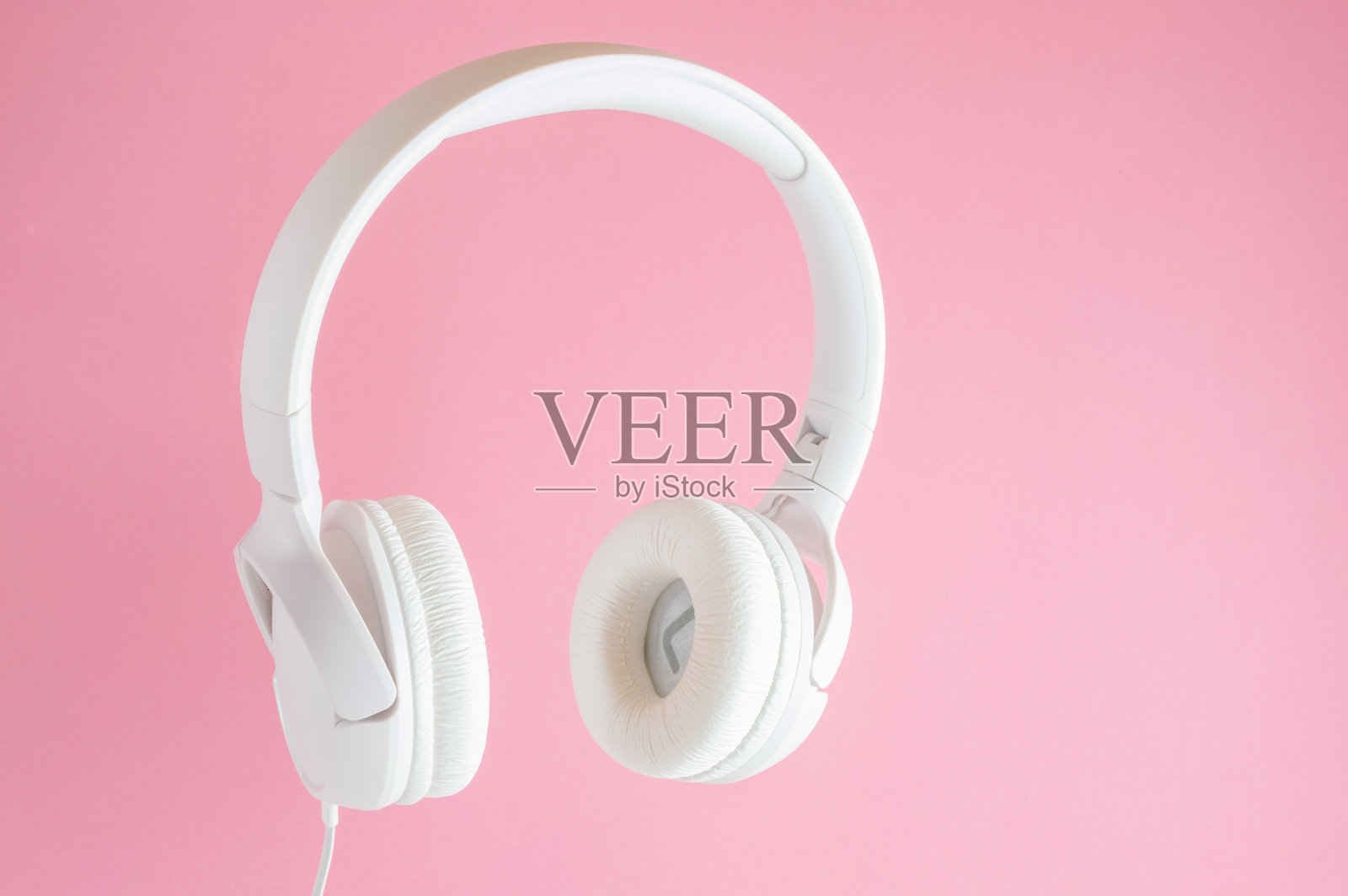 粉色背景的白色耳机。音乐的概念。照片摄影图片
