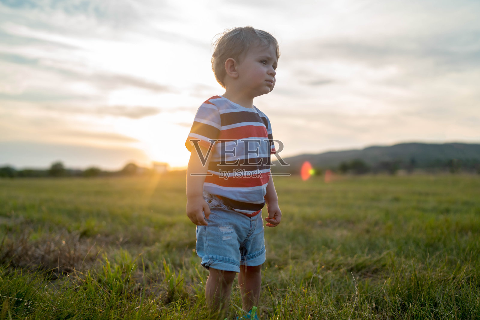日落时分,一个小孩在高高的草地上散步照片摄影图片