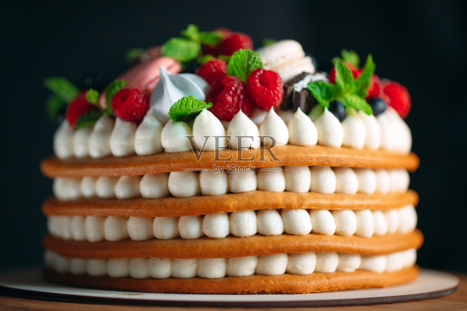 水果蛋糕。用浆果装饰的蛋糕,放在黑色背景的木架上。照片摄影图片