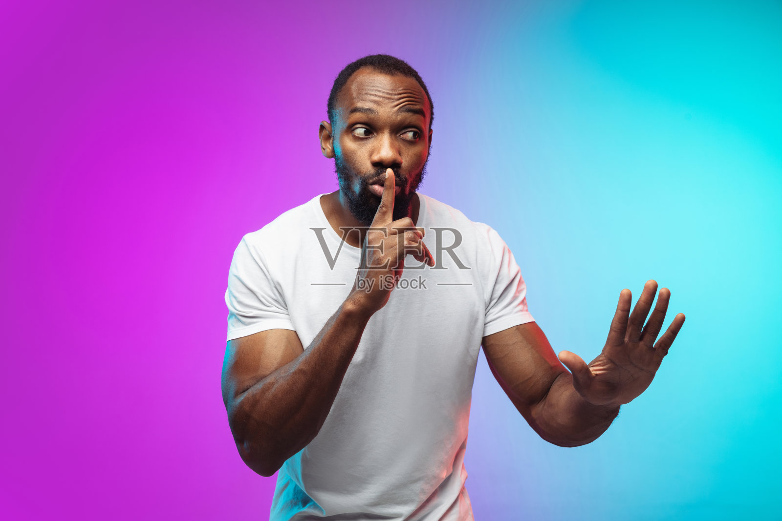 非裔美国年轻人的肖像在渐变工作室背景霓虹灯照片摄影图片