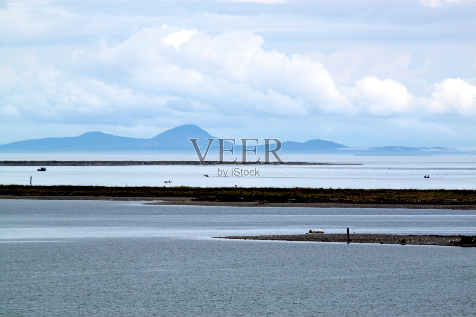 海景和海岸线与动态多云的蓝天与倒影在平静的水照片摄影图片