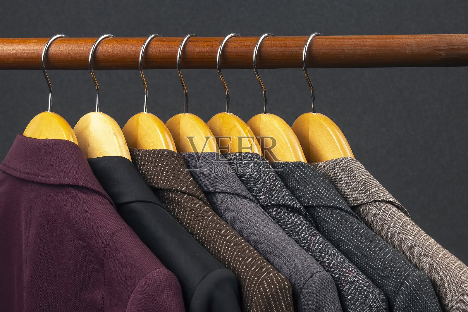 不同的女性办公室的经典夹克和衬衫可以挂在衣架上存放衣物。时尚服装款式的选择照片摄影图片
