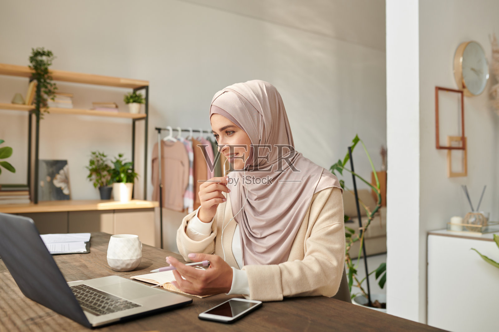 现代穆斯林妇女戴着头巾在家工作,参加在线会议,与同事讨论一些事情照片摄影图片