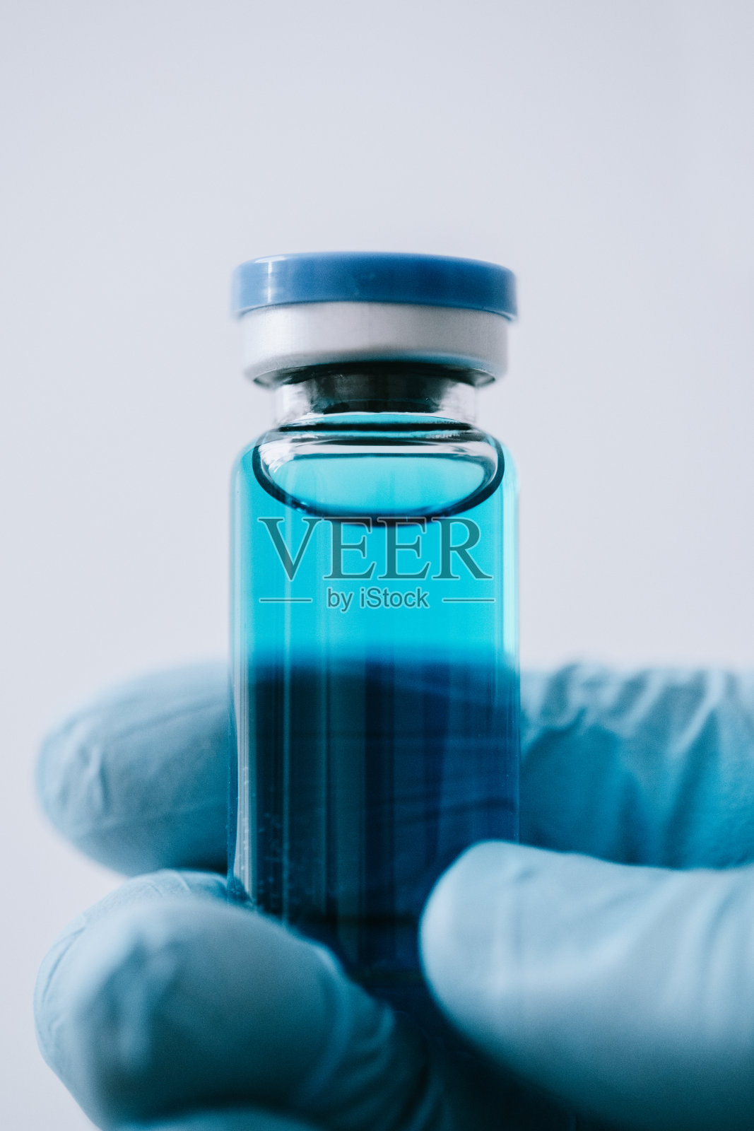 戴着手套手持疫苗瓶照片摄影图片